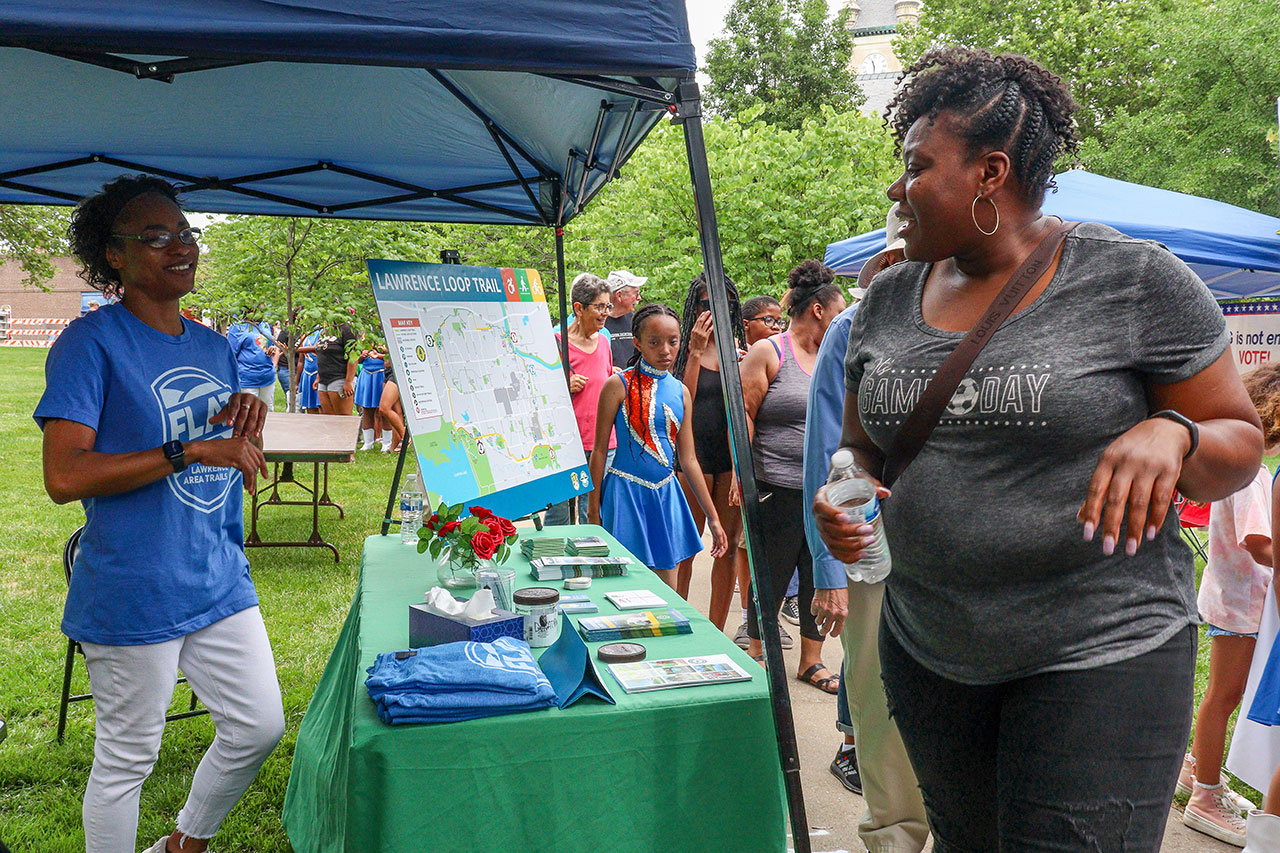 People gathering information about the Lawrence Loop at FLAT's table at Juneteenth