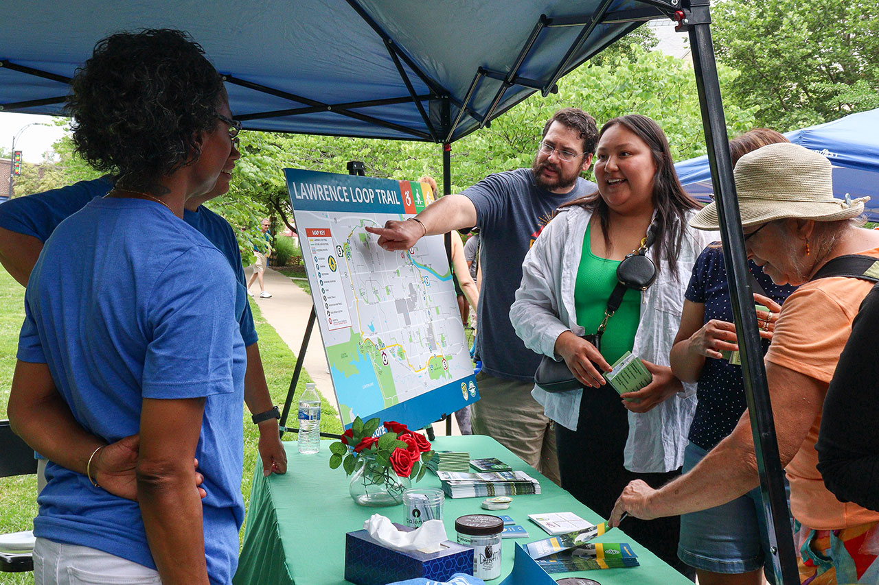 People gathering information about the Lawrence Loop at FLAT's table at Juneteenth