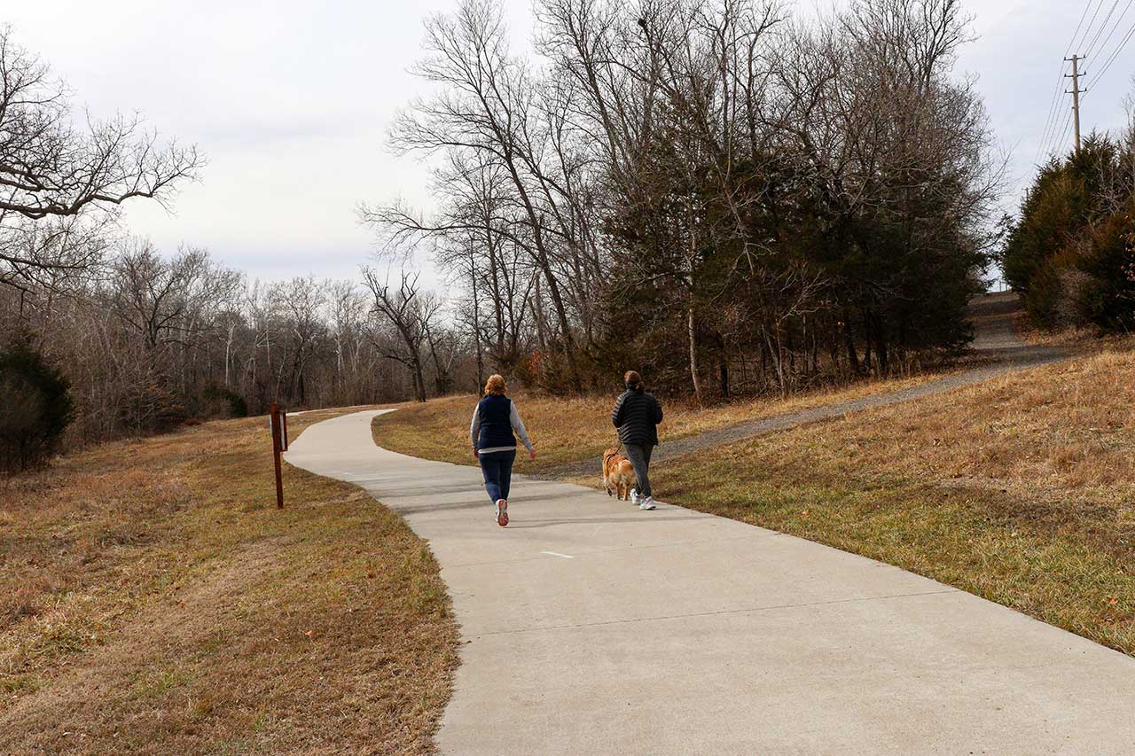 Two women walking a dog on the trail
