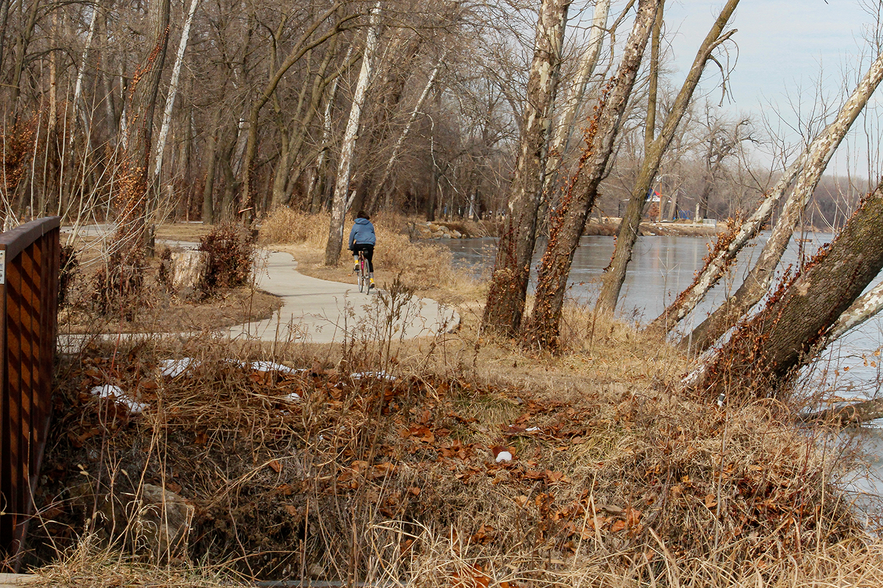 A woman riding her bike on the trail, which passes along the Kansas River
