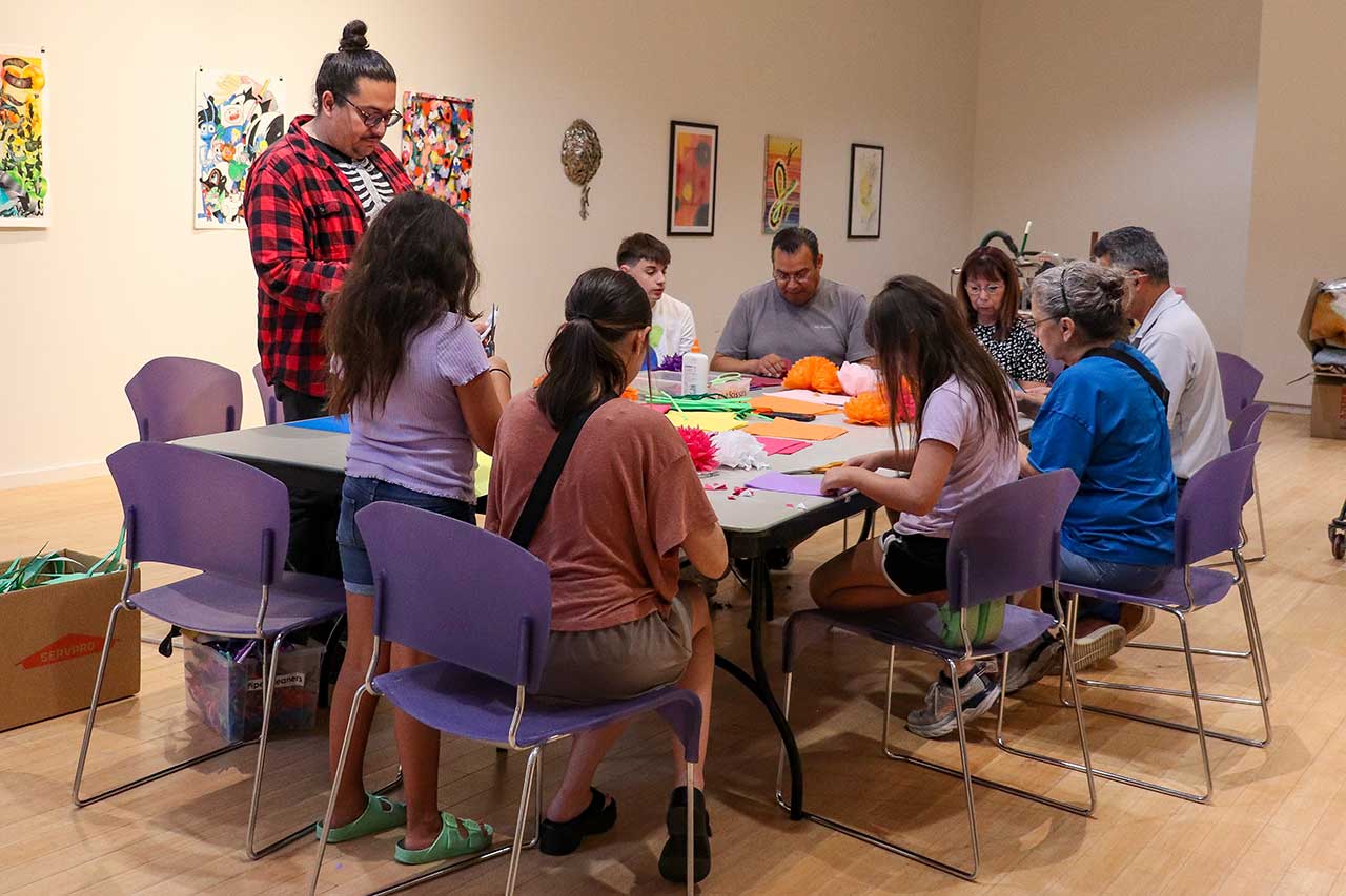 Family members gathered to create paper flowers for the exhibit with visiting artist Justing Favela