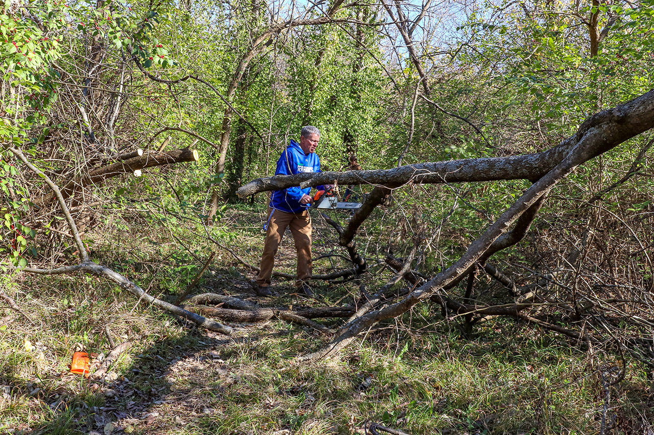 Teacher Eric Nelson using his chainsaw to cut bigger branches