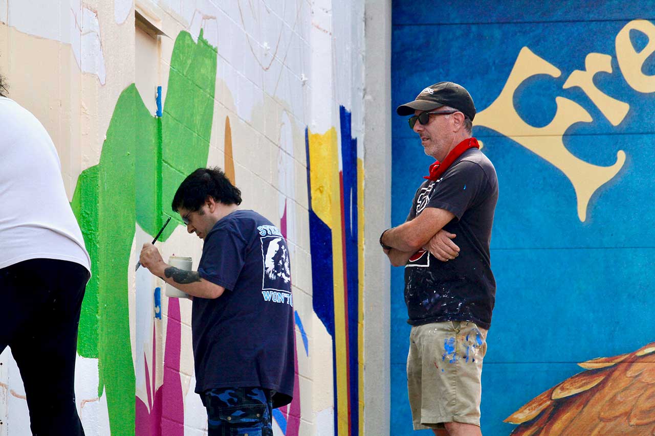 Artist Dave Lowenstein supervising people painting on the mural